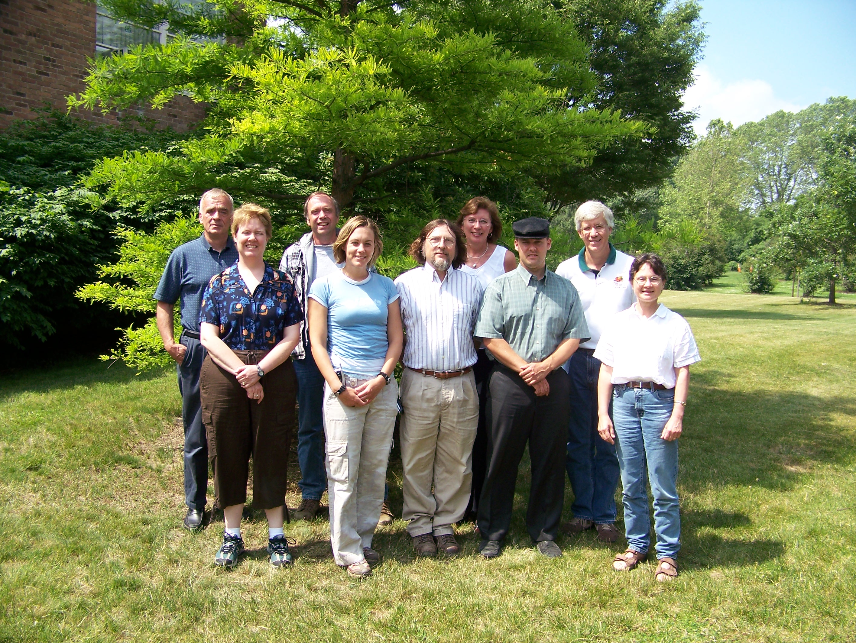 Nine people of the Cornell Vegetable Program pose for a group photo outside a building with a tree behind them.