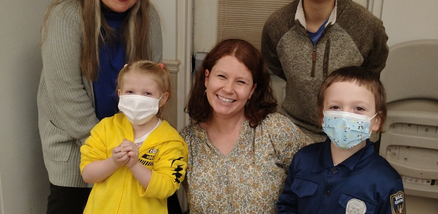 A woman and two small children smile for a photograph