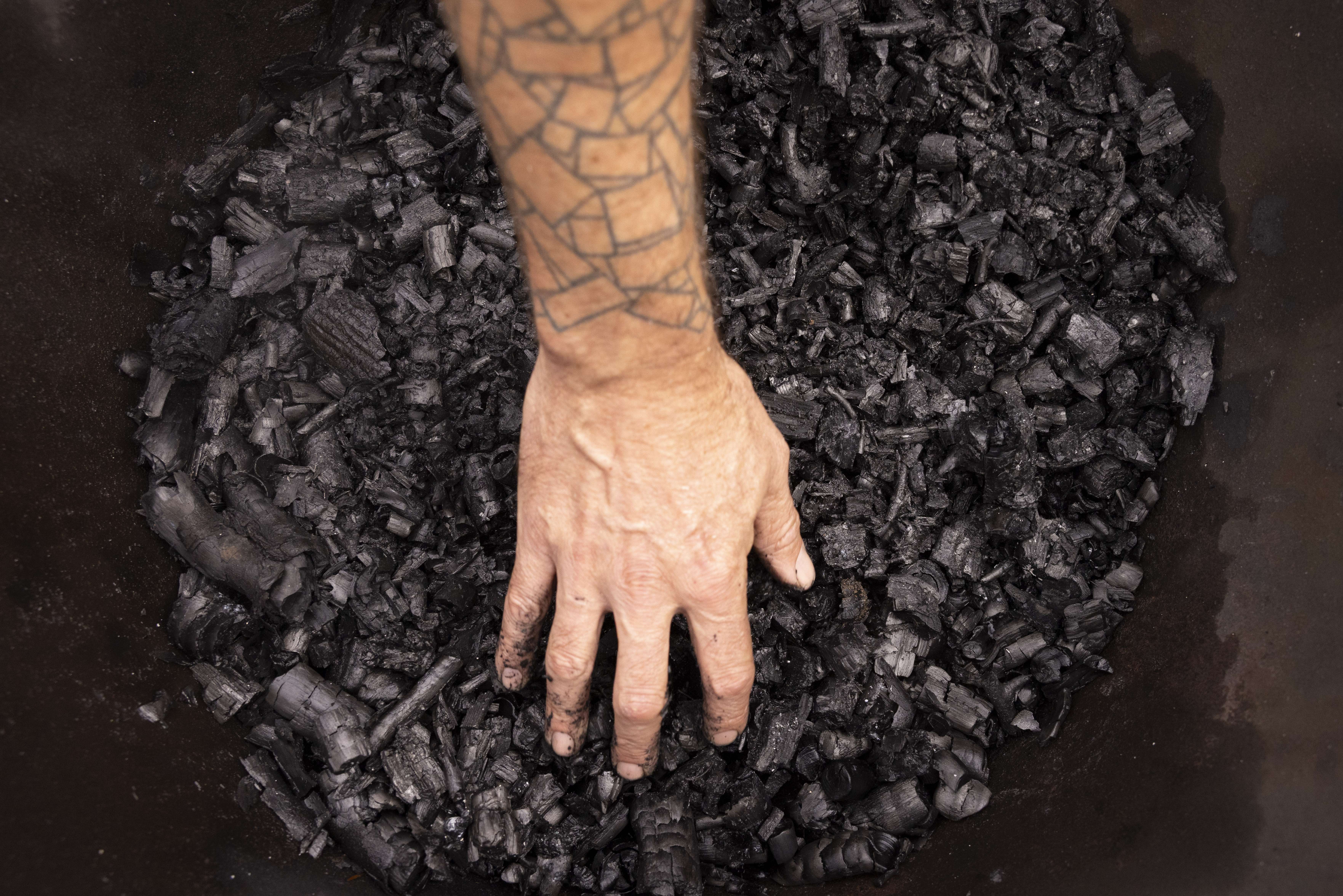 A hand touches biochar.