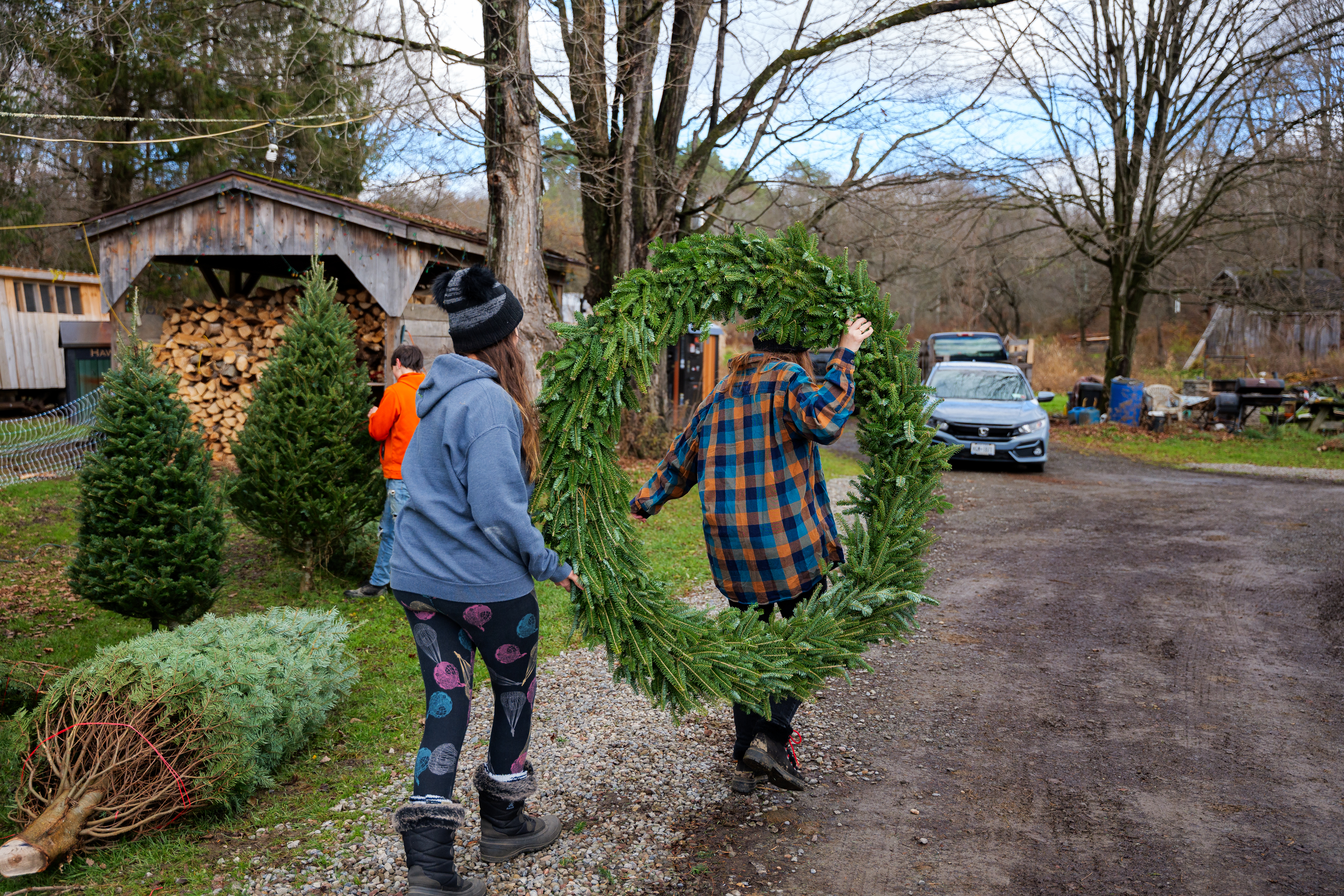 two women carrying a large holiday wreath