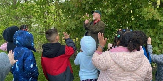 A man showing children different types of leaves