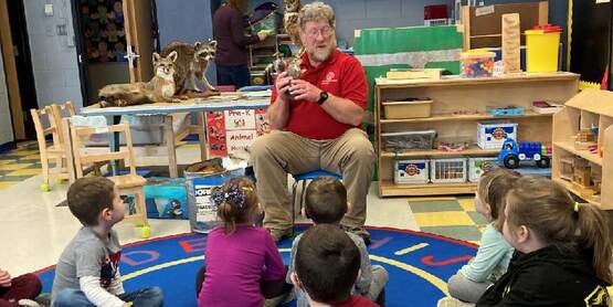 a man showing taxidermy animals to children during a nature presentation