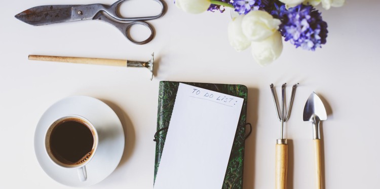 written to do list surrounded by garden tools next to a cup of coffee.