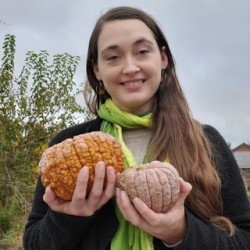 A photo of Kathryn Brignac holding two small pumpkins.