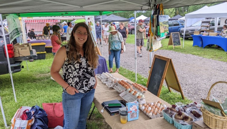 Amy at a farmers market with a display of eggs for sale