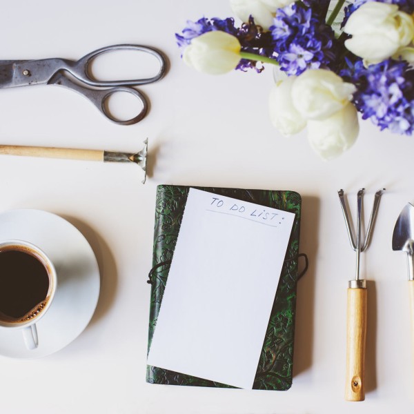 written to do list surrounded by garden tools next to a cup of coffee.