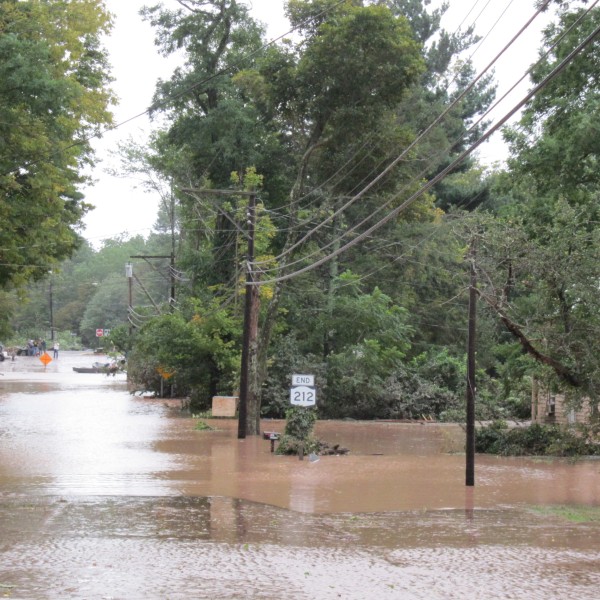 Flooding in Mount Tremper following Tropical Storm Irene in 2011. The road is submerged in brown flood waters that creep up to houses.