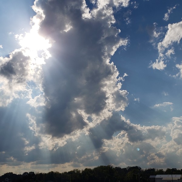 blue sky sun peeking through clouds and rays of sun