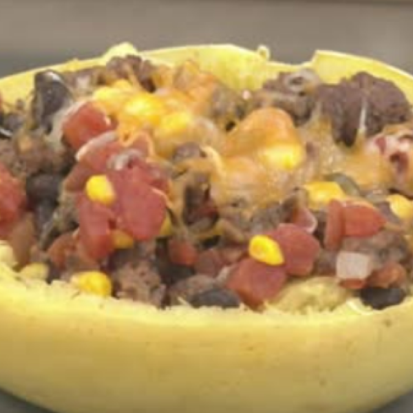 spaghetti squash boat filled with ground beef, onions, tomatoes, beans, and cheese