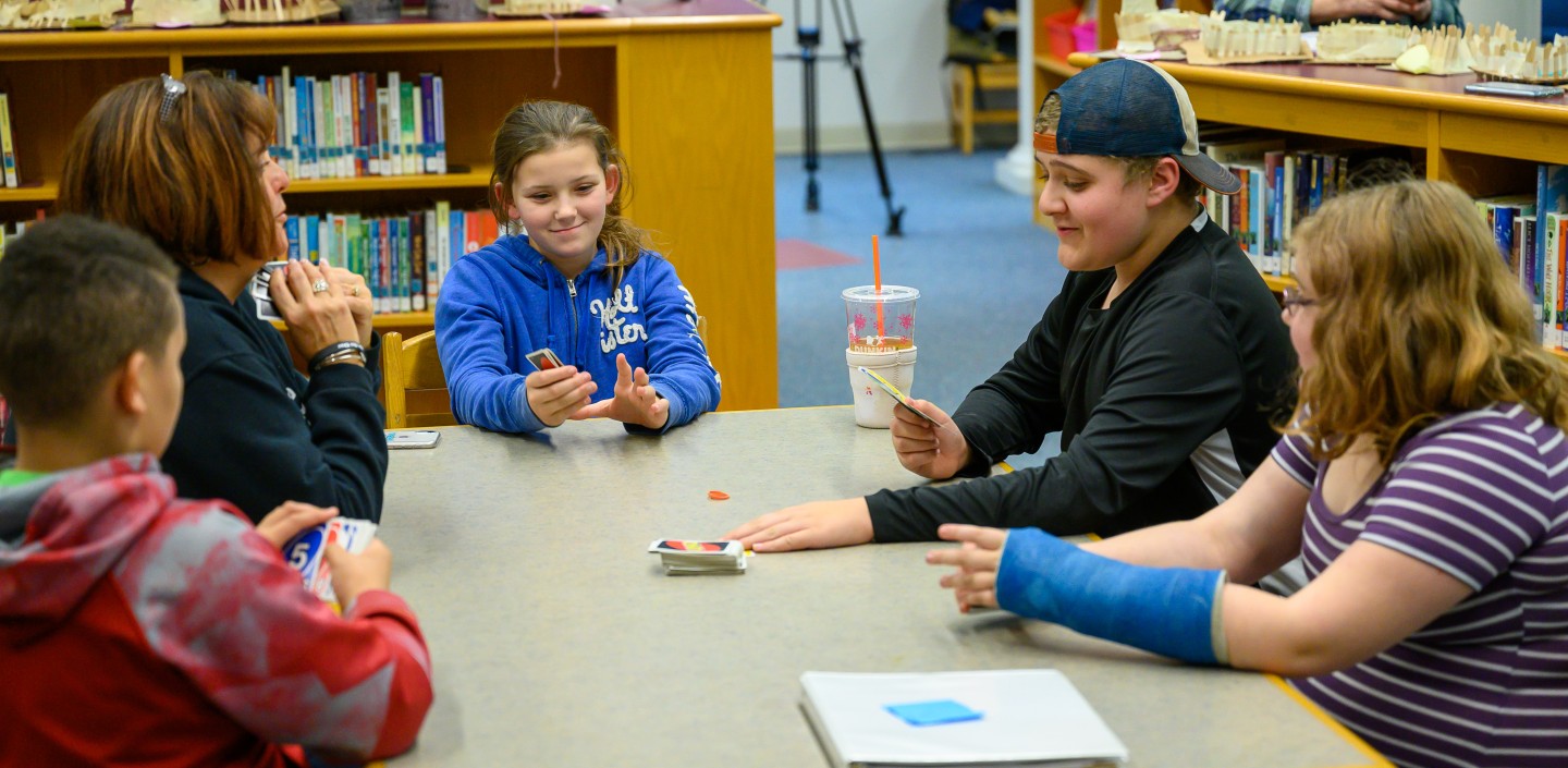 group of children and an adult playing Uno