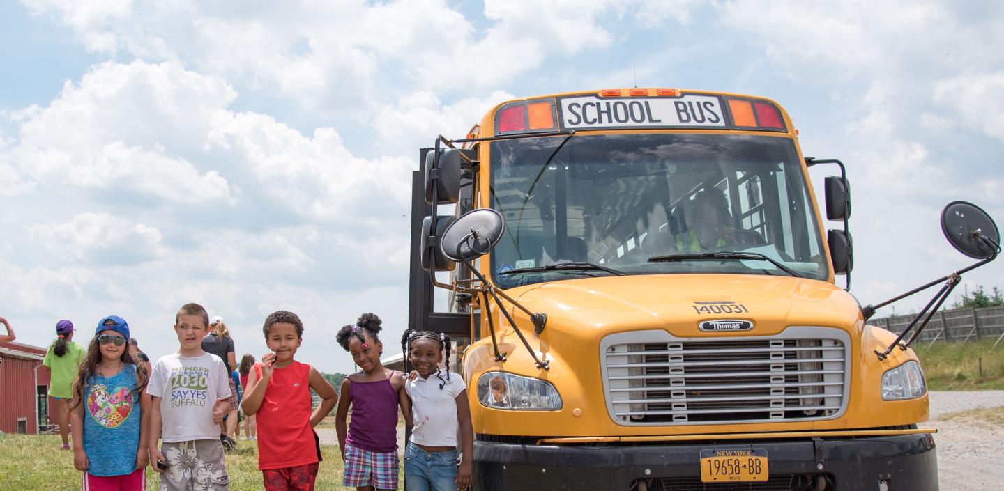 students posing for picture outside of bus