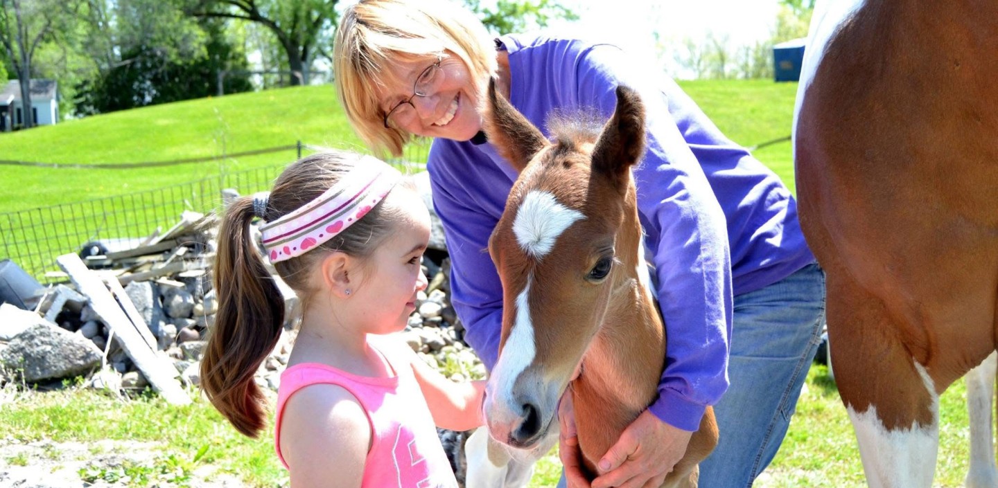 Lady and young child petting a horse
