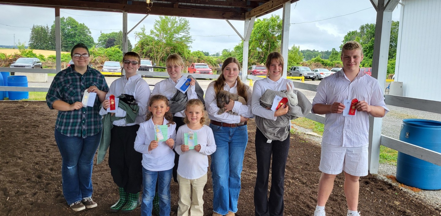 Youth standing outside holding green prize ribbons