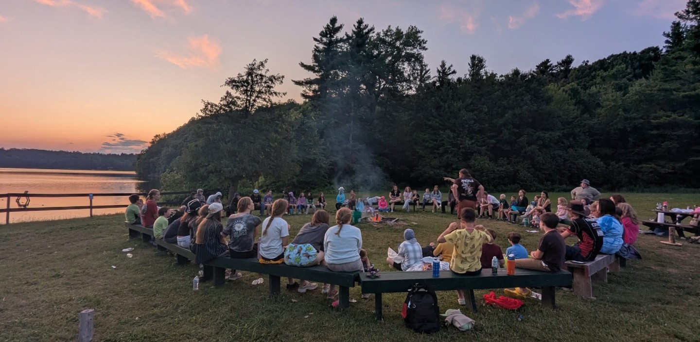 campers around campfire at sunset