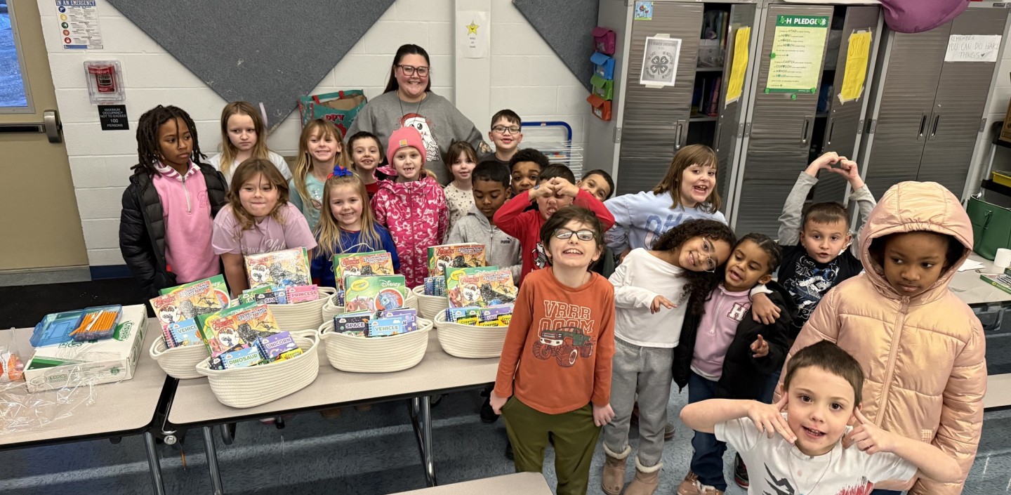 Students standing behind a table with goodie baskets filled with activities