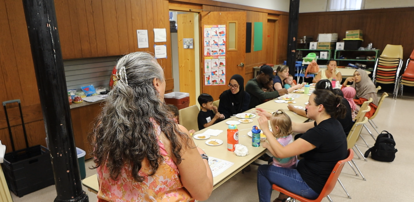 View over the shoulder of an educator teaching nutrition to parents of young children.