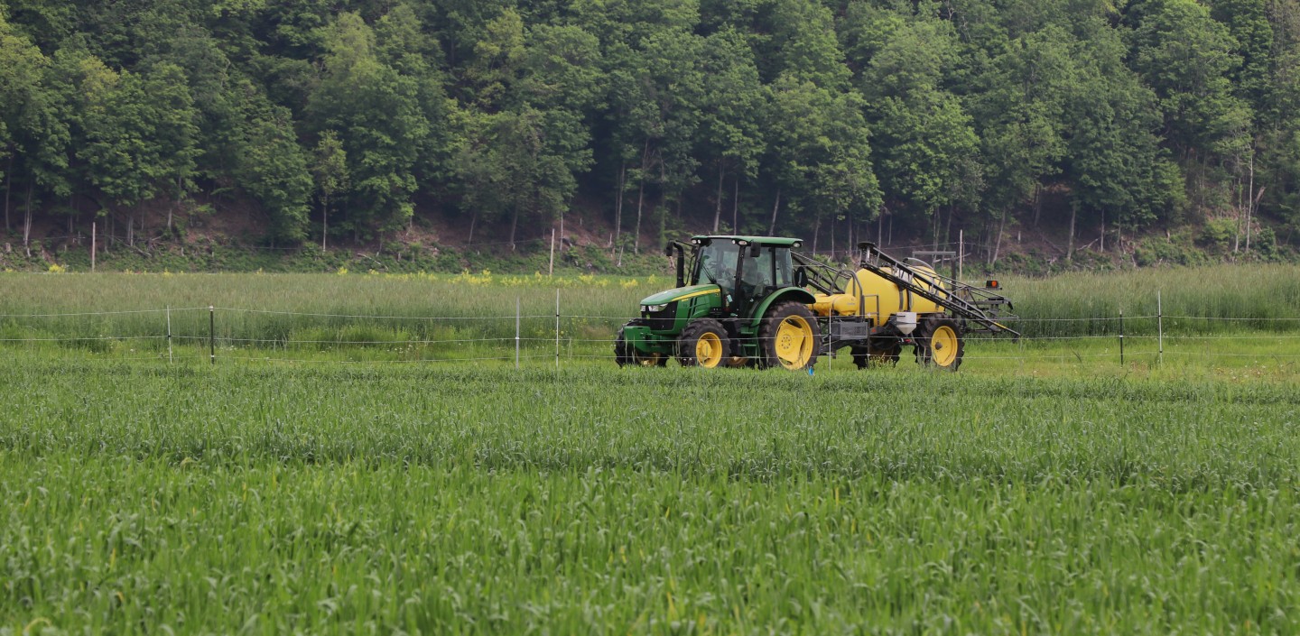 A tractor driving through a green field at the Hudson Valley Farm Hub.
