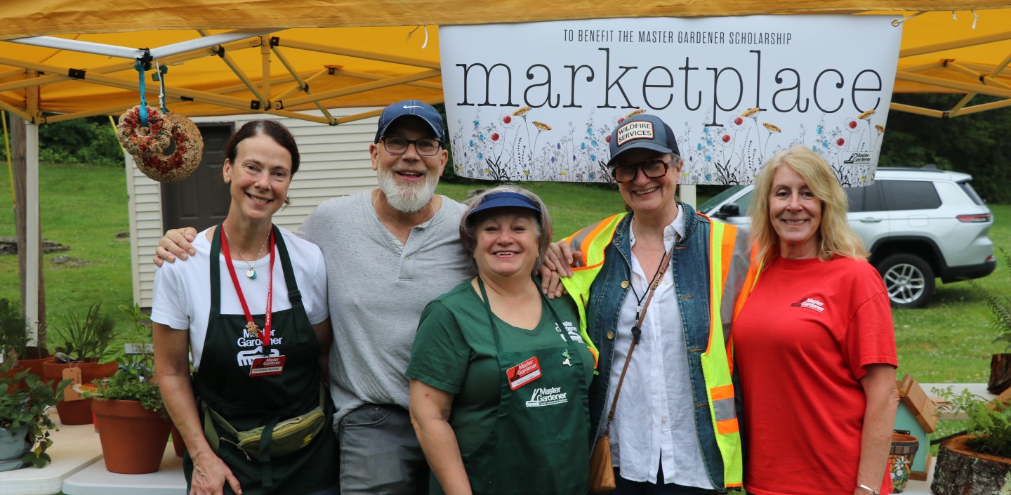 A group of Master Gardener Volunteers posing in front of the "Master Gardener Marketplace" that raises money for the Master Gardener Scholarship fund.