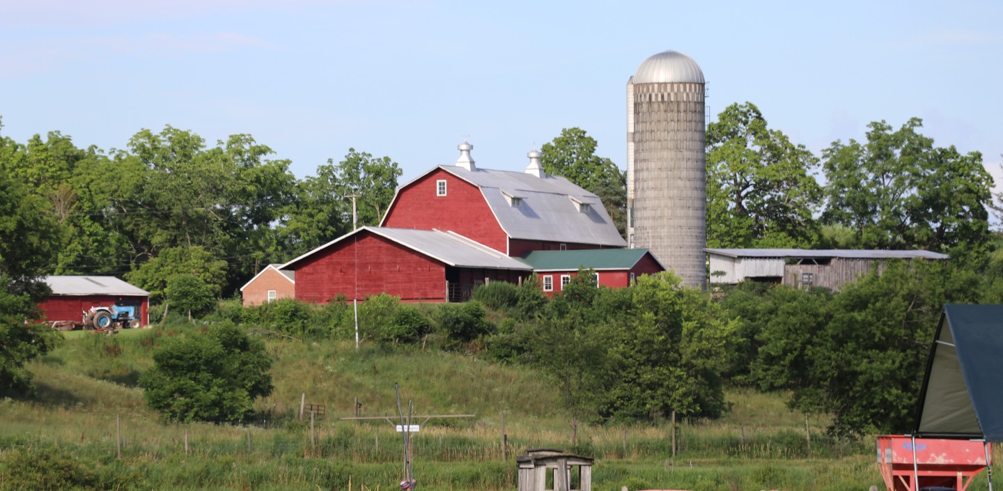 A red barn and grey silo sitting on top of a hill on the Kelder's Farm property in Kerhonkson, NY.
