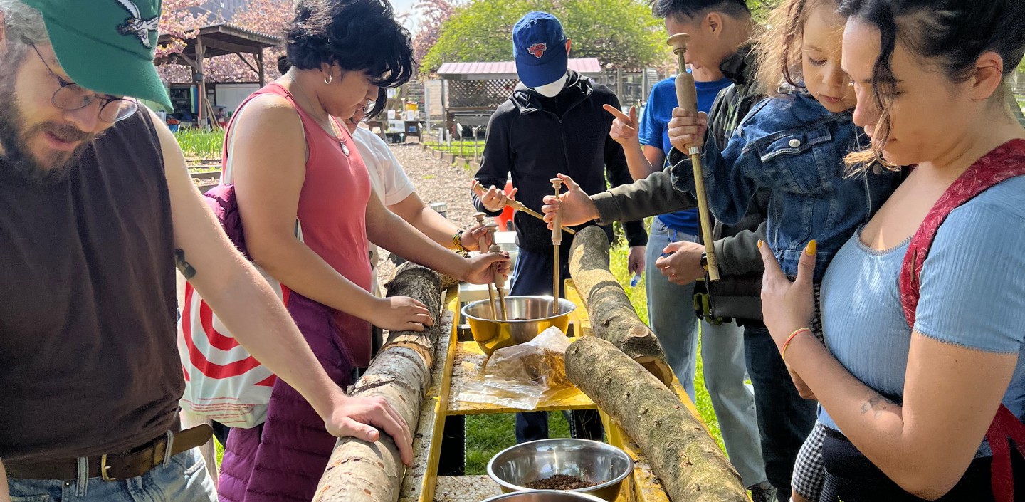 People stand on either side of a custom-made log mushroom inoculation table.