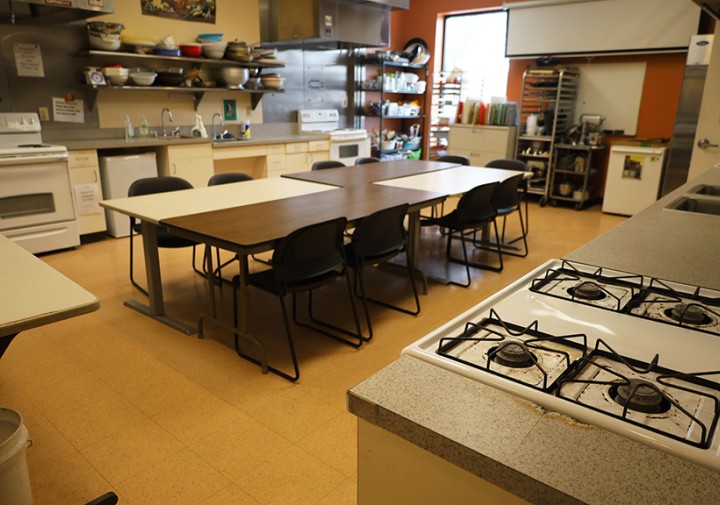 View of stoves, tables, and countertops in a large kitchen space.