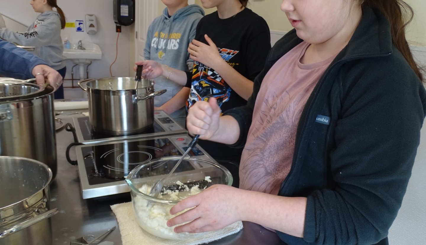 A girl stirs a bowl of dough in a cooking class