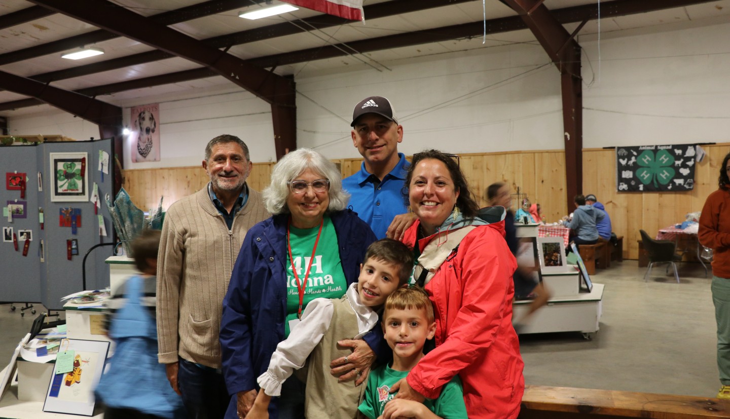 A family poses for a photo in the Youth Building, there are two children and 4 adults in the photo.