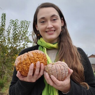 A photo of Kathryn Brignac holding two small pumpkins.
