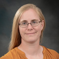 Headshot of Elizabeth Buck: A woman with blonde hair, wearing glasses.