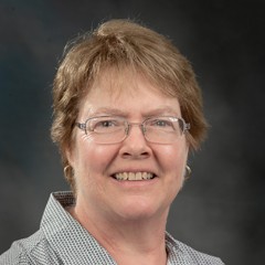 Headshot of Julie Kikkert: A woman smiling and wearing glasses.