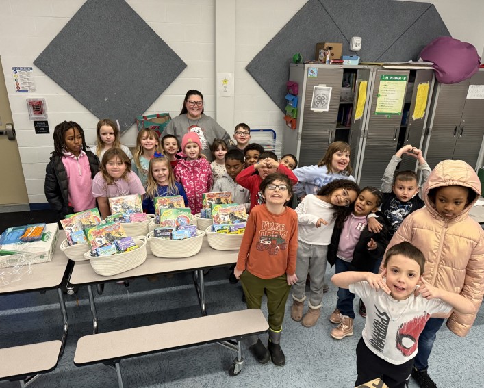 Students standing behind a table with goodie baskets filled with activities