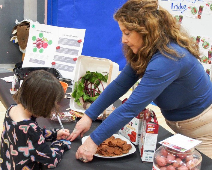 Staff help student try a beet