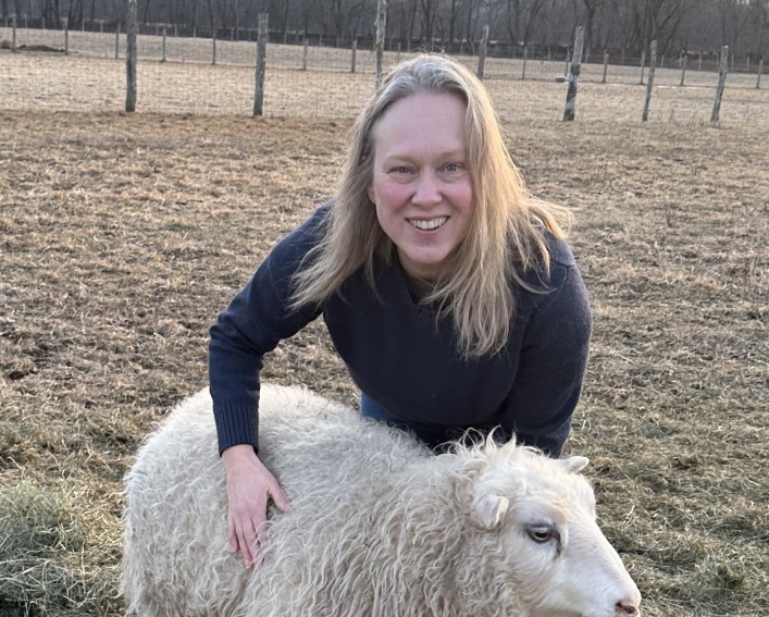 Farmer stands with her sheep.