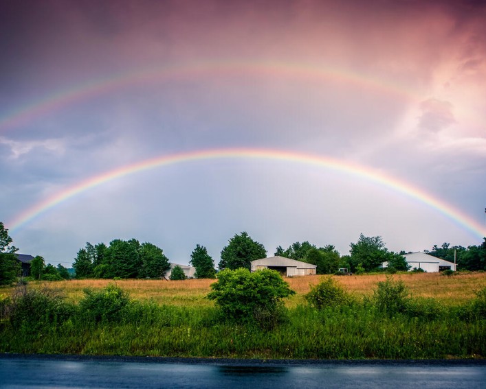 A double rainbow over a farm taken from a roadside.