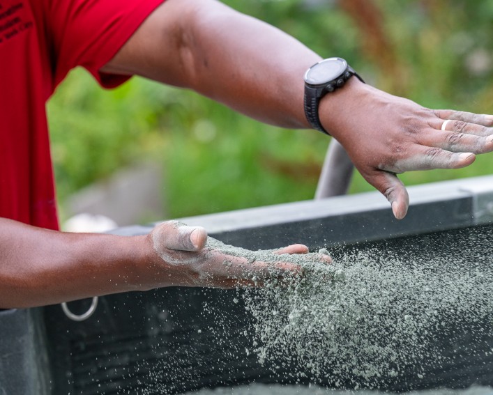 Close up of rock dust being swiped out of the right hand of a person by his left hand. The dust is scattered midair and falling from his hand.