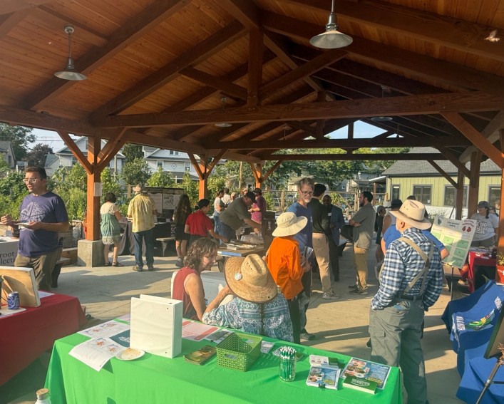 Participants engage with tabling organizations and their demonstrations while outside under a pavilion.