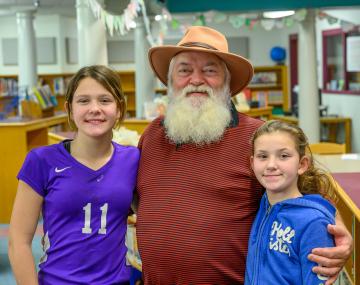 a man with a long white beard stands with two children