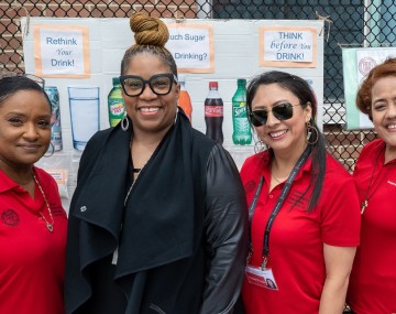 Four women stand in front of a display of healthy eating information