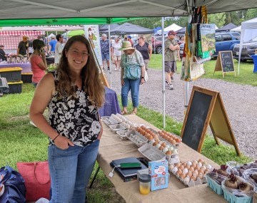 Amy at a farmers market with a display of eggs for sale