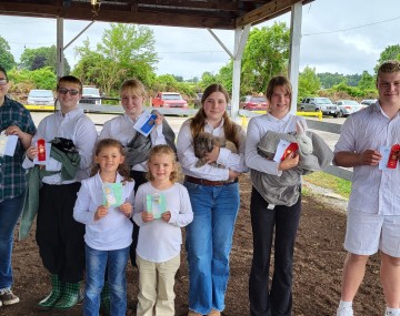 Youth standing outside holding green prize ribbons