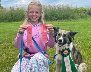 4-H youth next to dog holding ribbons won at fair
