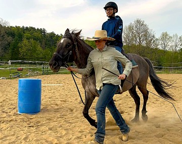 Woman leading horse and rider around barrel