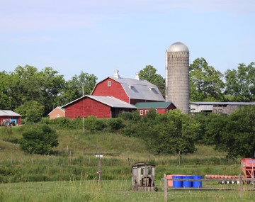 A red barn and grey silo sitting on top of a hill on the Kelder's Farm property in Kerhonkson, NY.