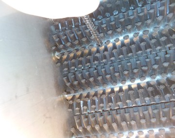 Looking inside a brush washer with stainless steel axles and bundles of bristles. Several brush sets are visible.