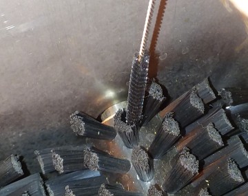 Close up of a bottle brush being used to get into a bundle of bristles on a brush washer.