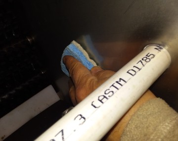Close up looking into a produce washer. A hand is holding a scrub sponge to clean the interior wall of the machine.
