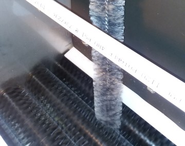 Dryer vent brush being put down into a brush washer system between the brush sets.