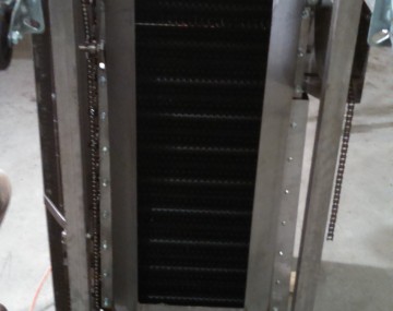A brush conveyor washer tipped on one end, revealing the underside of the machine.