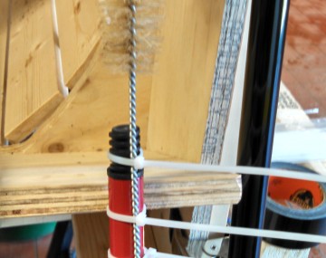 Three zip ties hold a wire handled brush onto the end of long broom handle.