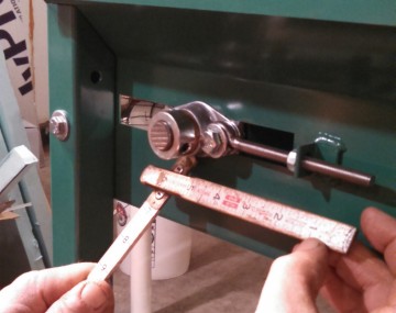 Close up measuring the location of the nut on the tension rod at the end of a conveyor produce washer.